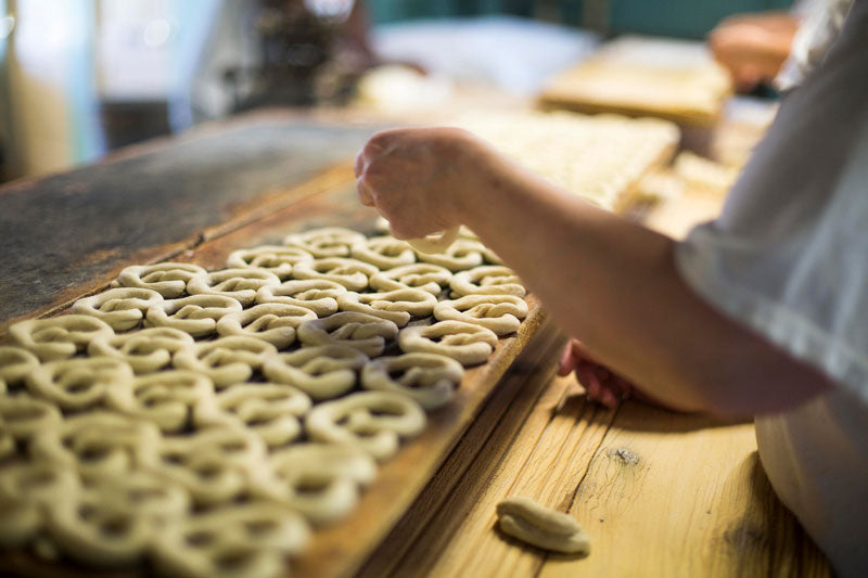 Handmade sourdough pretzel bakery twisting pretzels by hand before going in the oven.