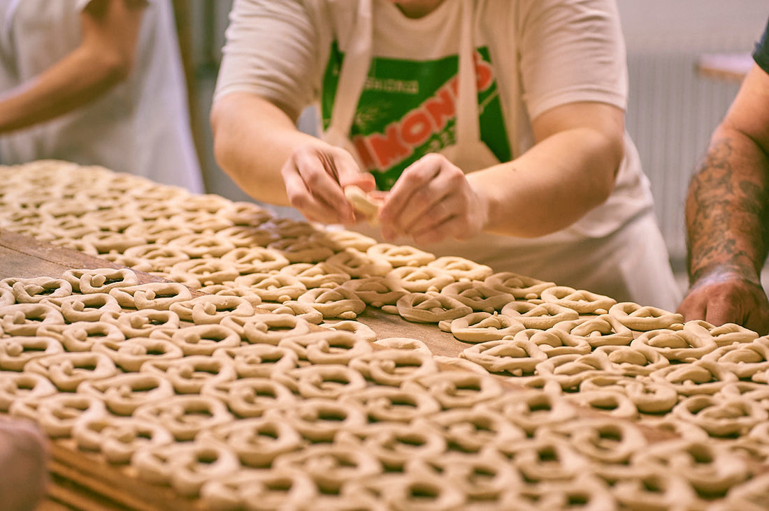 Bakers twist handmade sourdough pretzels, resting them before they go in the oven.